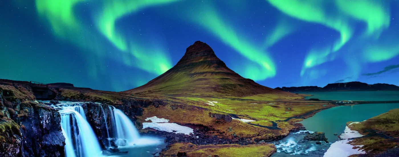 The Northern Lights over a mountain and waterfall in Iceland
