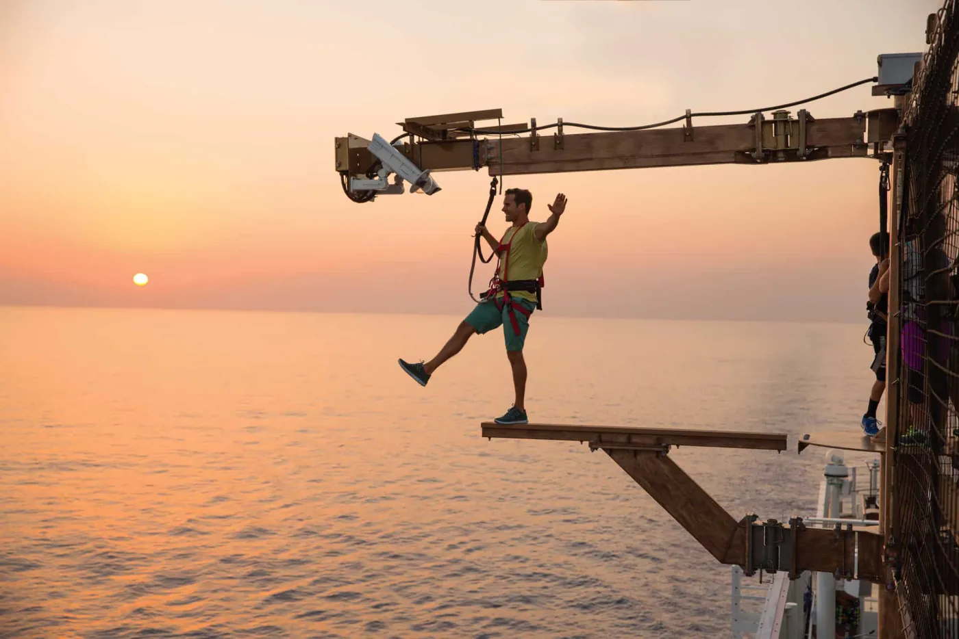 A guest on The Plank above the sea at sunset