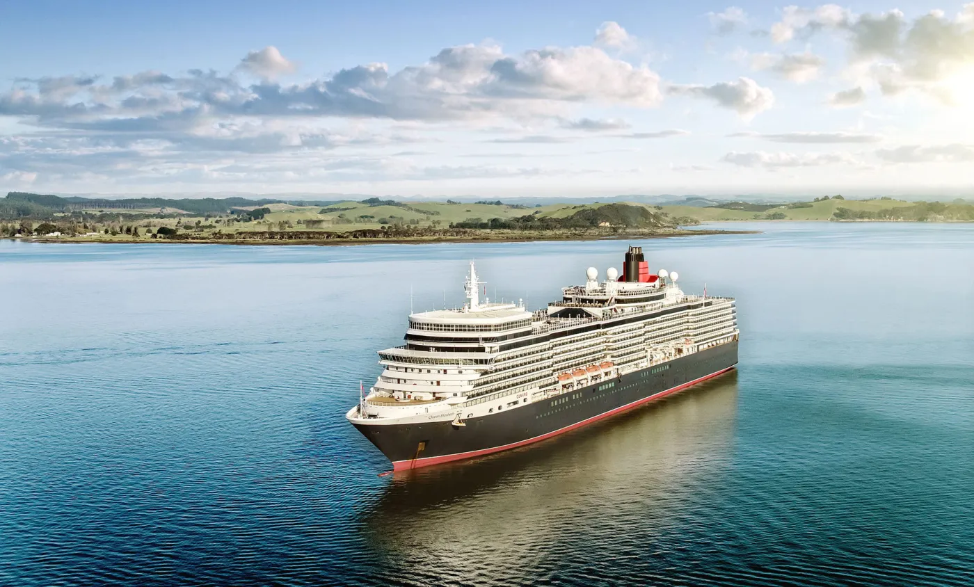 A Cunard Queen at anchor in a green bay